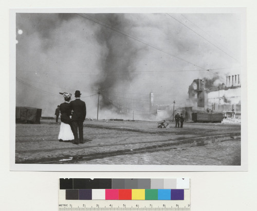 [Man and woman in street watching fire. Near Ferry Building. From near same location as FN-11937.]