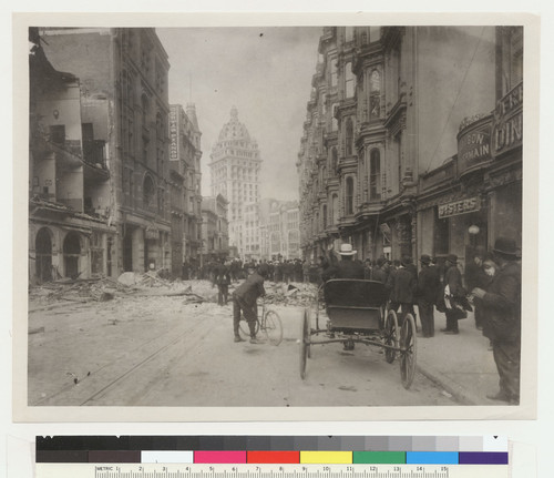 O'Farrell St., San Francisco fire of April 18, 1906. Note name of A.T. Leonard on window of Phelan Bldg. Geo. de Yrioste (his brother-in-law) is sitting in (a rented) buggy awaiting him. A.T.L. [Crowd gathered in street watching Call Building burning in distance.]