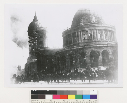 [Crowd in street at City Hall. Fire burning in distance.]