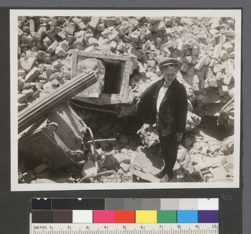 [Boy posing among rubble. Unidentified location.]