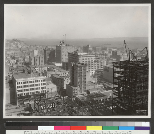 [Cityscape from above circa Kearny and Post Sts. looking northeast toward Wholesale District. Telegraph Hill in distance, left; Merchants' Exchange Building and Mills Building, center.]