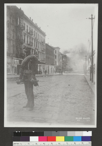 [National Guardsman patroling Kearny St. with fire in background.]