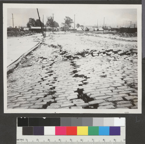 [Earthquake damage to street. Colulmbia Square refugee park in distance.?]