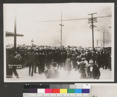 [Crowd gathered in street to observe fire. Unidentified location.]