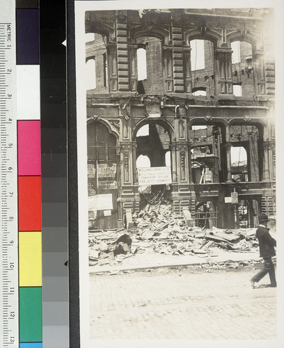 [Street scene showing ruins and business signs.]