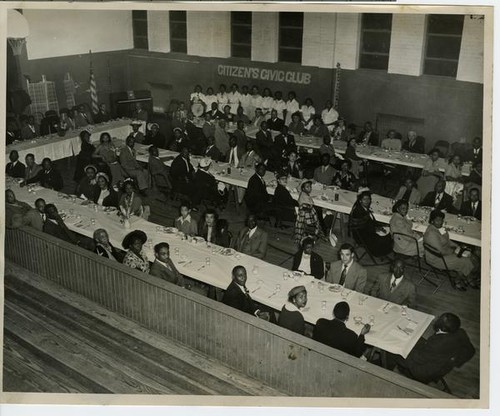 Attendees at banquet tables with a banner of the Citizen's Civic Club in background