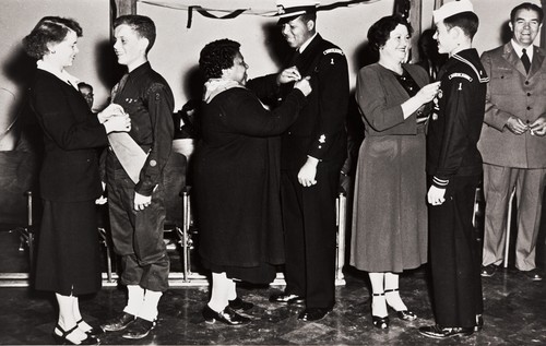 Eulamae Whiteside Gatewood pinning Eagle Scout badge on Leander Gatewood, Santa Maria's first black Eagle Scout, at a meeting of the Sea Explorer Scouts at the American Legion Hall in 1950