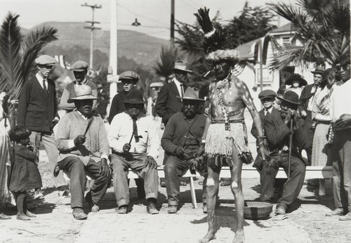 Dance performance by Bob Bautista (Tachi Yokuts) at Ventura County Fair : 1932, accompanied by men with clapper sticks. Left to right on bench: Jim Wilcox (Yokuts), unidentified man, Jose Juan Olivas (Ventureño Chumash), and Juan Solano (Migueleño Salinan)