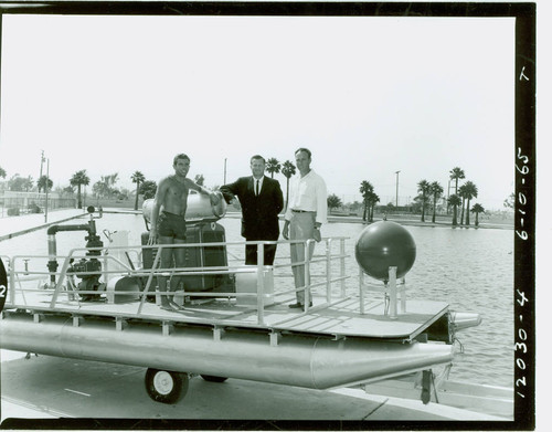 View of three men on pool cleaning boat at Alondra Park