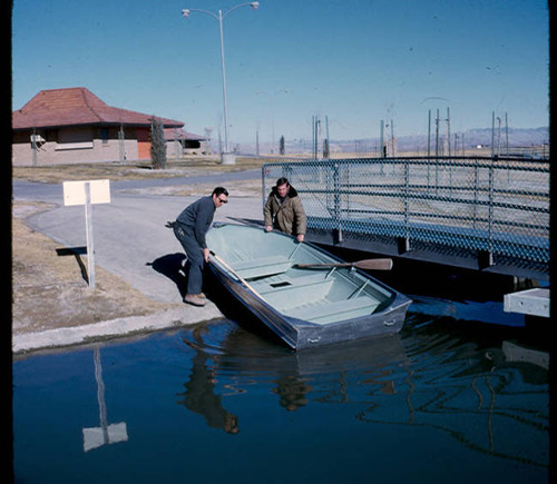 View of County of Los Angeles Department of Parks and Recreation employees putting a row boat into the lake at Apollo Park