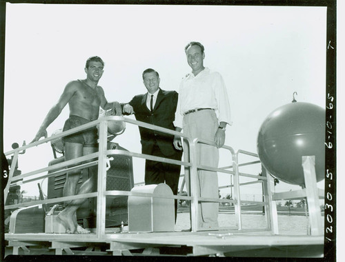 View of three men on trailered pool cleaning boat at Alondra Park