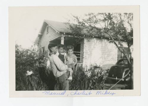 A young man holding 2 young children, Los Nietos, California