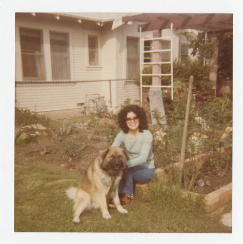 Rachel Barajas with a dog in the back yard of a residence, Los Nietos, California