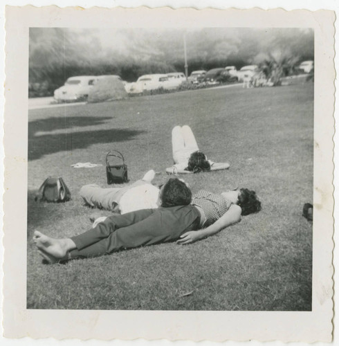 People lounge on grass in park