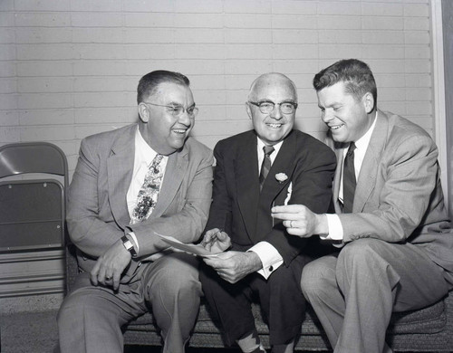 Three men sit at an association meeting
