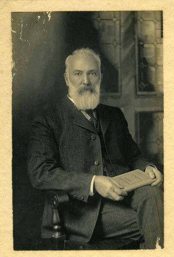 Portrait of Theodore Lukens seated holding a book