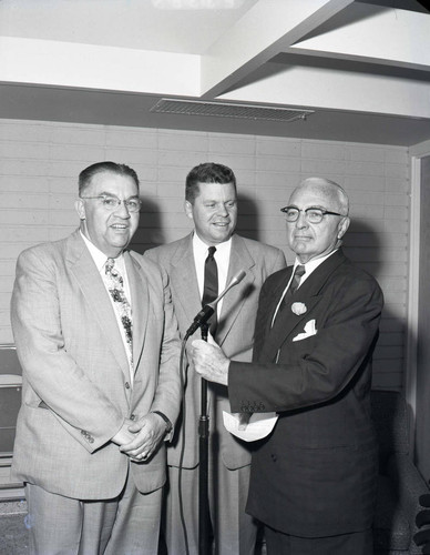 Three men behind microphone