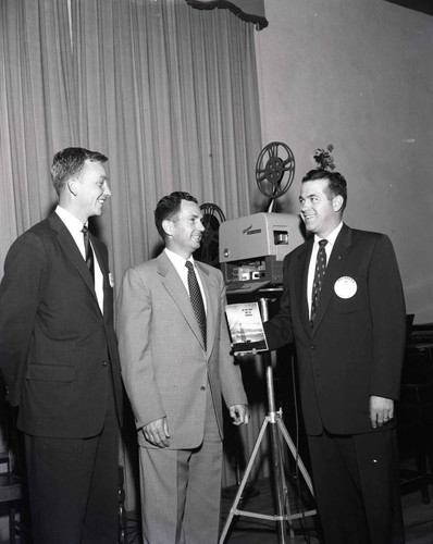 Men pose with film projector