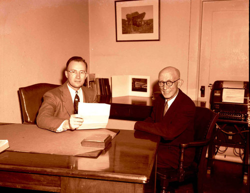 Mr. Moore sitting at his desk — Calisphere