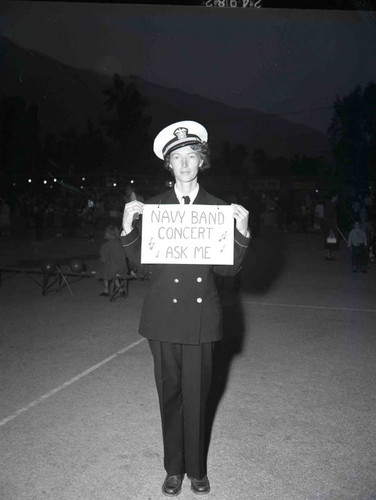 Young woman with a sign advertising the Navy Band Concert