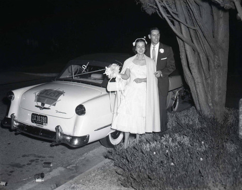 Bride and groom next to car