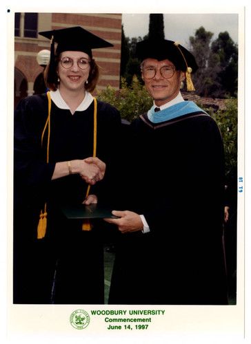 Ken Nielsen Presents a Student with a Degree at Commencement