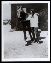 Emily Brown Childress Portwig with a horse outside her desert cabin, Victorville, 1920s-1930s