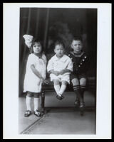 Three small African American children sitting on a bench, 1890-1900