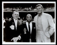 Chuck Connors with Emmett Ashford and another man in a baseball stadium, 1960s