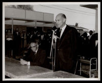 Loren Miller seated beside a man at the opening of the English Square office building, Los Angeles, 1964