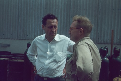 Oceanographers Roger Revelle and John D. (John Dove) Isaacs on the dock discussing the research work that they will be doing for the Midpac Expedition (1950). This expedition involved Scripps Institution of Oceanography and the U.S. Navy which discovered the Mid-Pacific Mountain Range on the bottom of the Pacific Ocean and confirmed Darwin's theory about the origin of atolls. Scientists were surprised to find that the seafloor was young, deep and rocky, not flat, old and filled with sediments. Measurements of continental heat flow from the ocean raised questions about the history of the Pacific Ocean basin that were later answered by Plate Tectonics theory. 1950