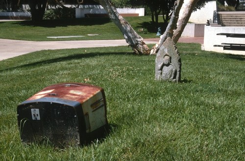 Something Pacific: detail: carved stone buddha contemplating old television set