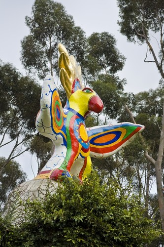 Sun God: upshot of sculpture with top of vine-covered arch and euclyptus trees