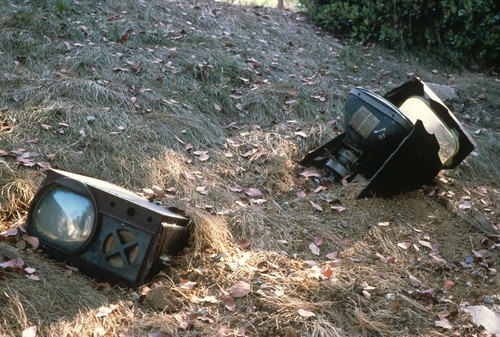 Something Pacific: detail: ruined television sets half buried on dry slope