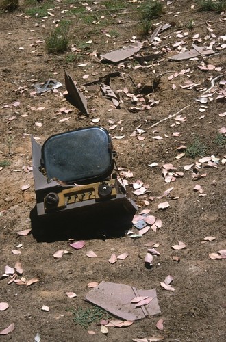 Something Pacific: detail: ruined television sets half buried on dry slope