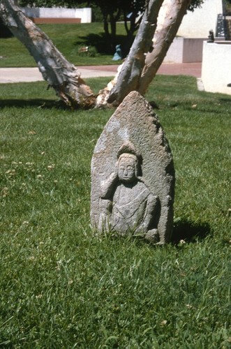 Something Pacific: detail: carved stone buddha contemplating old television set