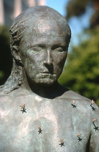 Standing: detail view of head and upper half of torso, with tiny representations of starfish configured as the constellation Virgo