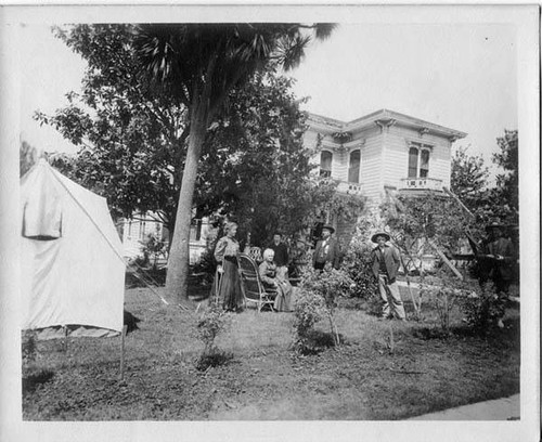 Family camping in front of earthquake-damaged home