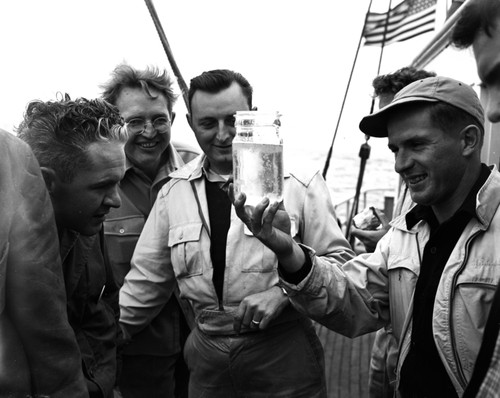 Unidentified Scripps Institution of Oceanography graduate students examine plankton haul on board E.W. Scripps (ship) off San Diego bay. 1947