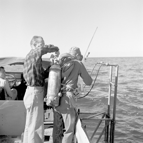 Scripps' Offshore sand ripple study. Converted DUKW used for aqualung dives---just outside surf line at La Jolla Shores, head of Scripps canyon, California. Douglas L. Inman is adjusting the diver's tank