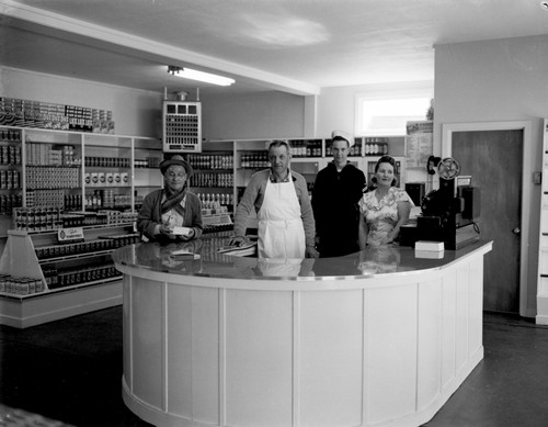 Opening of the Rite Price Market, Manager George Ludy and family behind counter. Man-around-town George (Smitty) Smith on left. Store burned down a year later, circa 1950