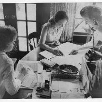 Mrs. Frank M. (Alberta) Jordan on phone, doing paperwork with Mrs. Robert Tate (center) and another woman