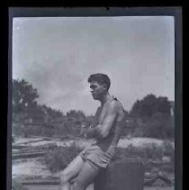 A man wearing a bathing suit sitting on a dock