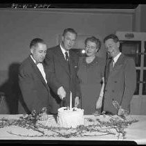 Three men, one woman and a cake with a candle