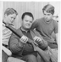 Sheriff Duane Lowe shows a rifle to son Rex and another family member