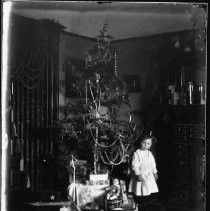Baby standing next to a Christmas tree
