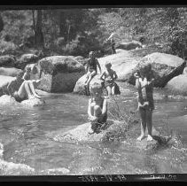 Children and adults playing and swimming in a river