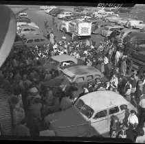 A crowd of people on a street with cars