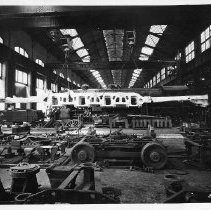 Interior view of the Southern Pacific Railroad Company's carbarn construction shops showing employees building and repairing railcars and locomotives