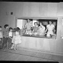 A group of children being served hot dogs